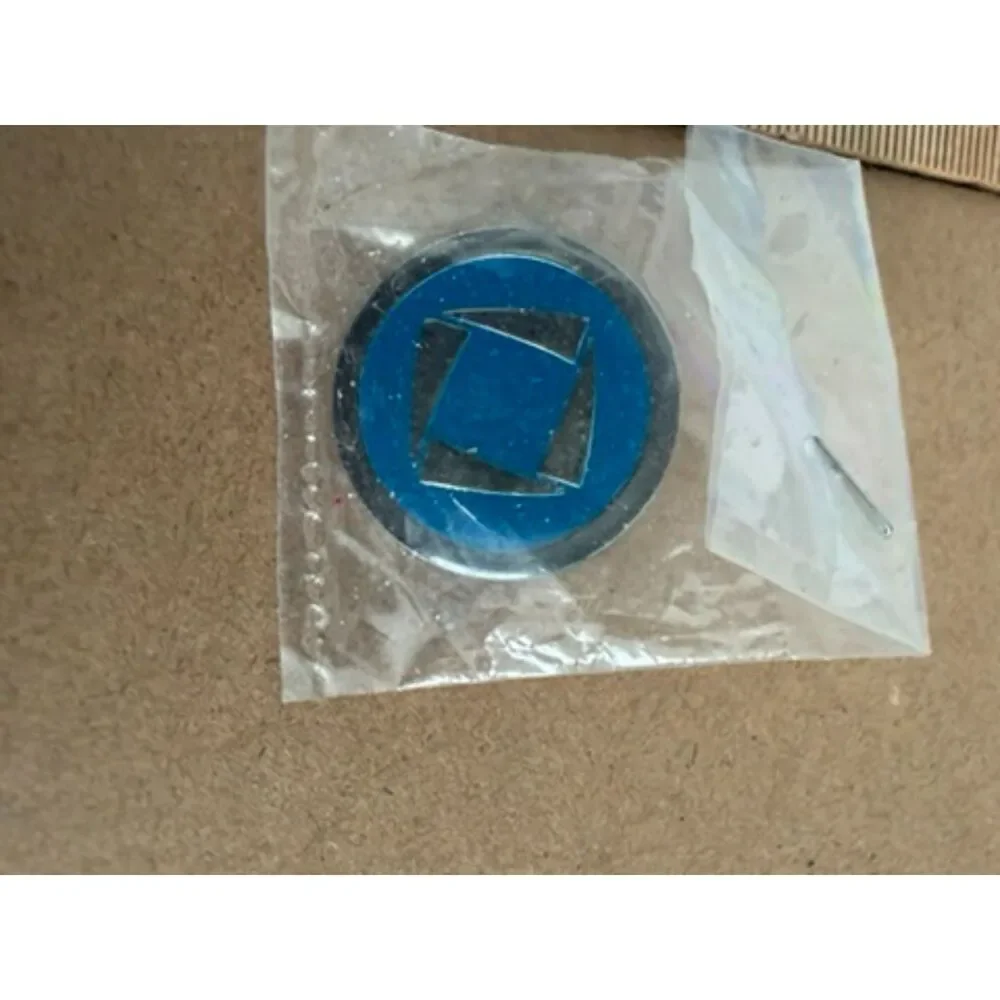 DECA logo pin  round white rim blue center with white shapes